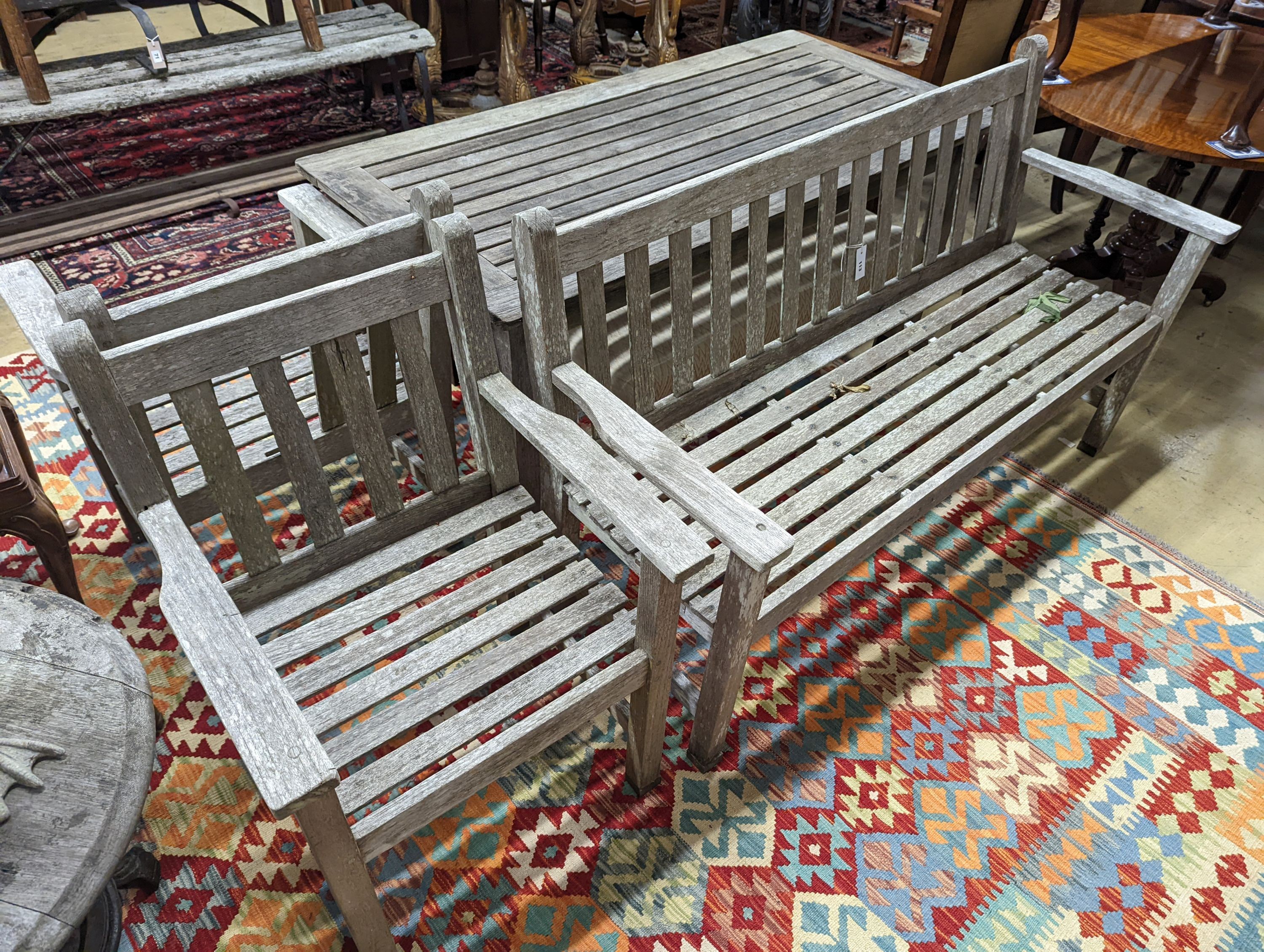 A Barlow type weathered teak garden suite, comprising rectangular table, length 149cm, depth 71cm, height 70cm, a bench and two armchairs